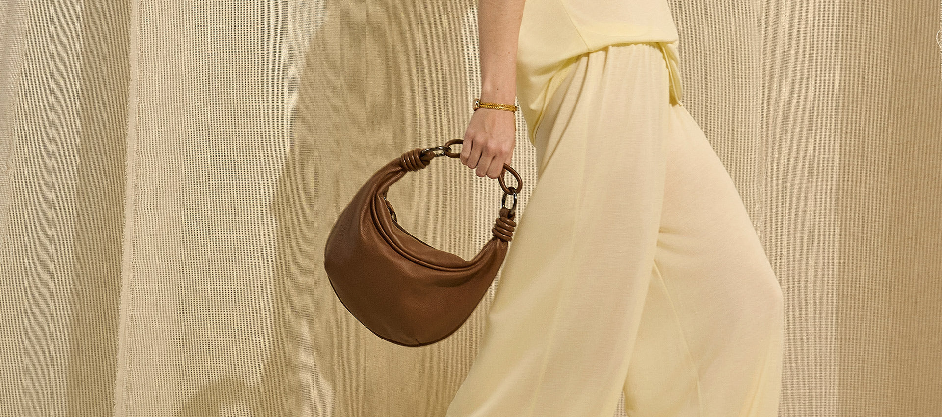 Banner de vitrine modelo usando bolsa de couro mini hobo marrom da marca Soleah
