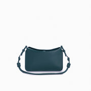 Flap Loop Soleah em couro verde: bolsa com aba frontal, formato compacto e alça longa para uso no ombro ou transversal; vista frontal com a alça longa posicionada ao redor da bolsa, evidenciando a opção de uso no ombro ou transversal.