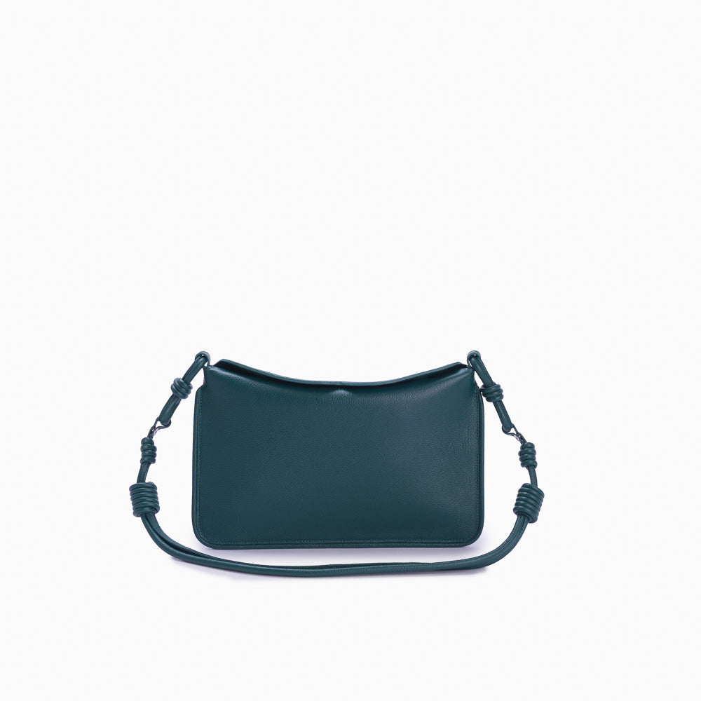 Flap Loop Soleah em couro verde: bolsa com aba frontal, formato compacto e alça longa para uso no ombro ou transversal; vista frontal com a alça longa posicionada ao redor da bolsa, evidenciando a opção de uso no ombro ou transversal.