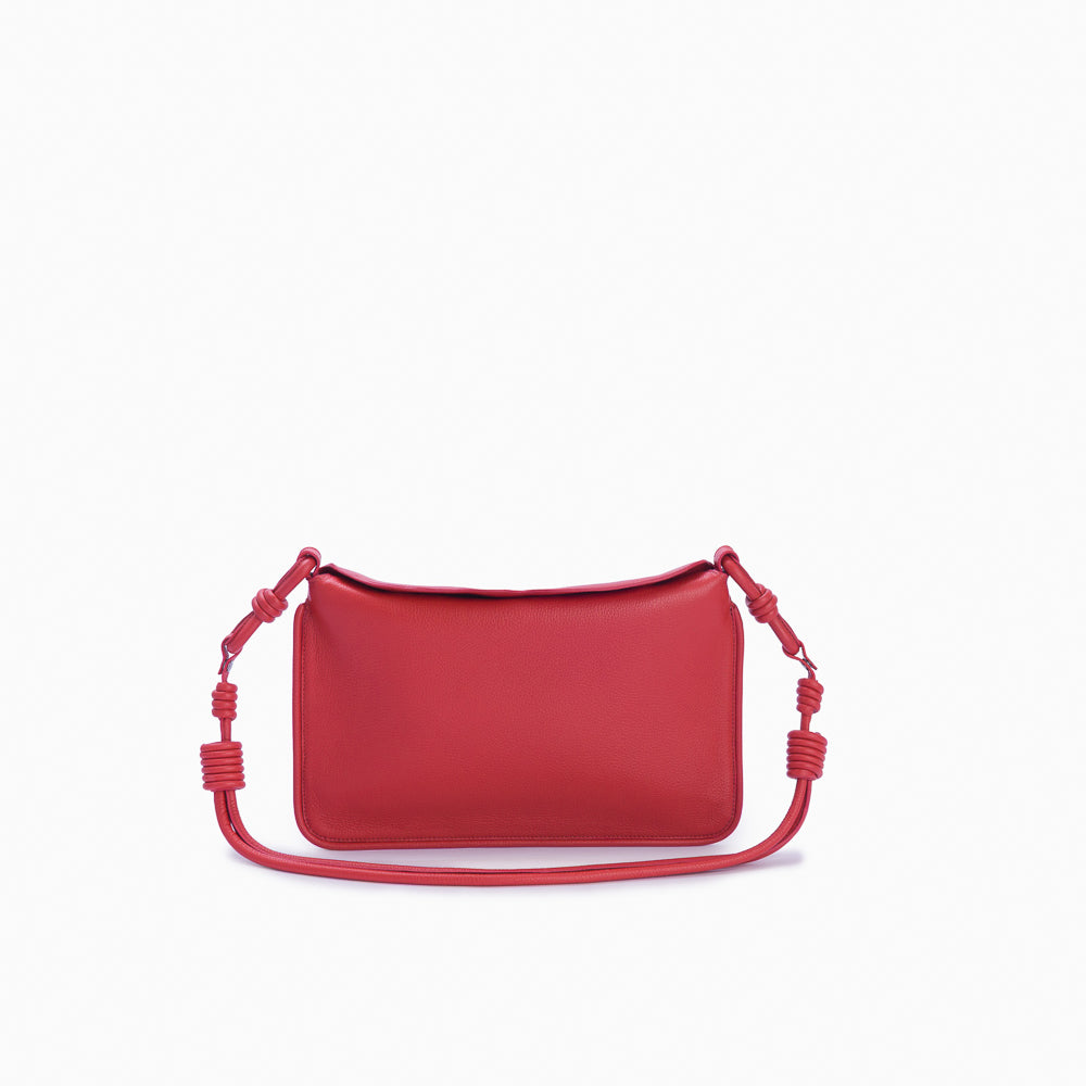 Flap Loop Soleah em couro vermelha: bolsa com aba frontal, formato compacto e alça longa para uso no ombro ou transversal; vista frontal com a alça longa posicionada ao redor da bolsa, evidenciando a opção de uso no ombro ou transversal.