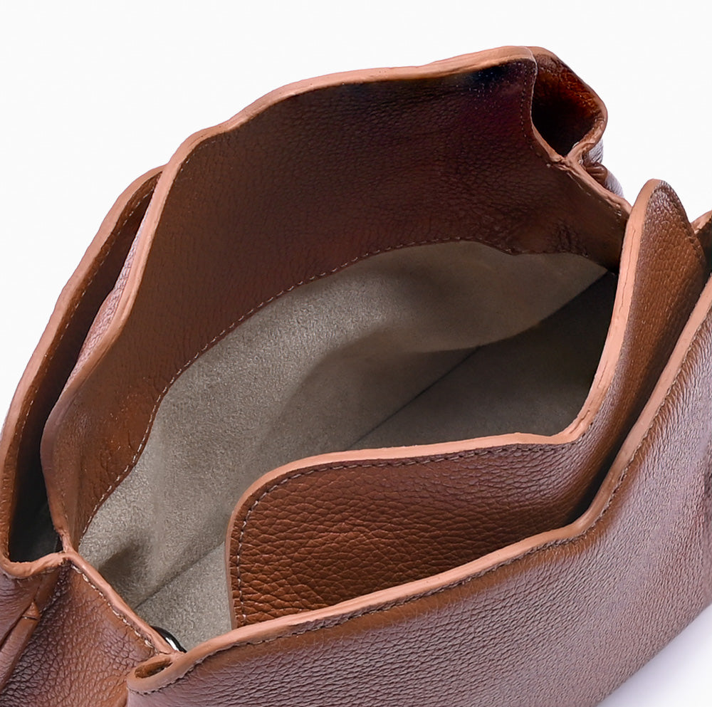 Handbag Loop Soleah em couro caramelo: bolsa de mão de formato compacto, com alça superior curta e acabamento de linhas orgânicas; bolsa aberta em detalhe, mostrando o compartimento interno, o forro e o acabamento das bordas.