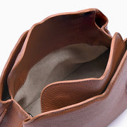 Handbag Loop Soleah em couro caramelo: bolsa de mão de formato compacto, com alça superior curta e acabamento de linhas orgânicas; bolsa aberta em detalhe, mostrando o compartimento interno, o forro e o acabamento das bordas.