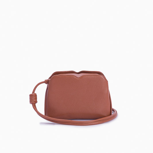 Handbag Loop Soleah em couro caramelo: bolsa de mão de formato compacto, com alça superior curta e acabamento de linhas orgânicas; vista frontal com a alça longa posicionada ao redor da bolsa, evidenciando a opção de uso no ombro ou transversal.