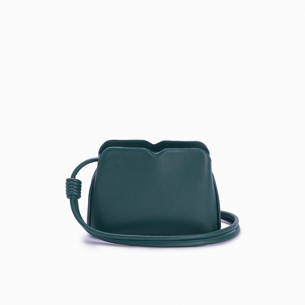 Handbag Loop Soleah em couro verde: bolsa de mão em couro de formato compacto, com alça superior curta e acabamento de linhas orgânicas; vista frontal com a alça longa posicionada ao redor da bolsa, evidenciando a opção de uso no ombro ou transversal.