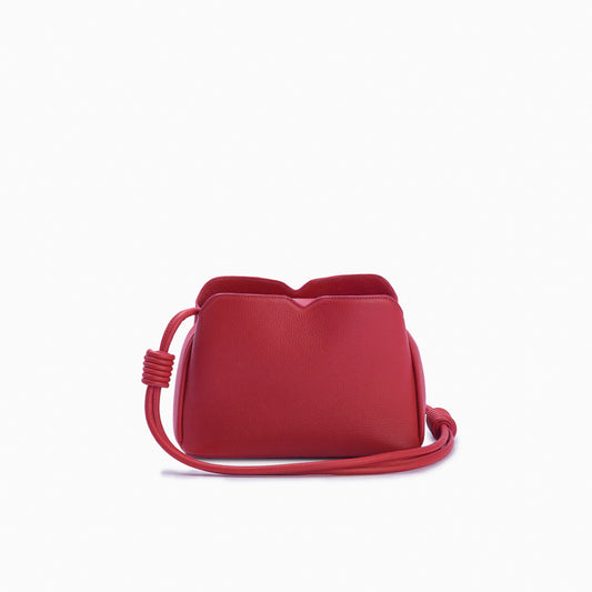 Handbag Loop Soleah em couro vermelha: bolsa de mão em couro de formato compacto, com alça superior curta e acabamento de linhas orgânicas; vista frontal com a alça longa posicionada ao redor da bolsa, evidenciando a opção de uso no ombro ou transversal.